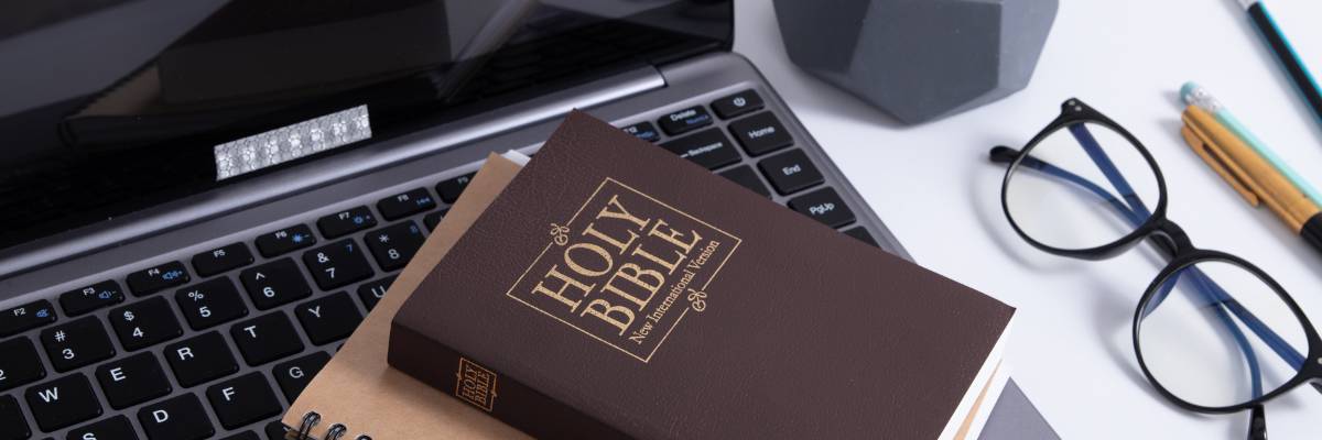 closed bible on open laptop